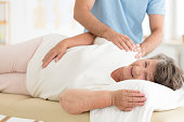Masseur massaging senior woman's shoulders