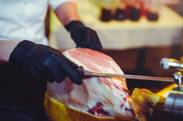 istock Sliced dried chamon prosciutto. A man cuts a jamon, a warm toned image. Selective focus point 882354476