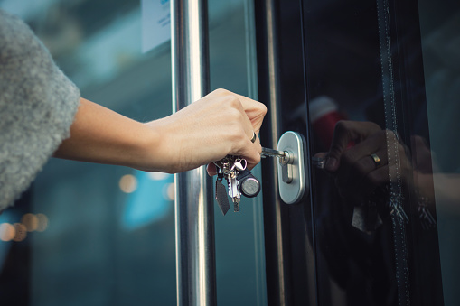 Close up of woman locking entrance door with a key. Person using key and unlocking apartment door.