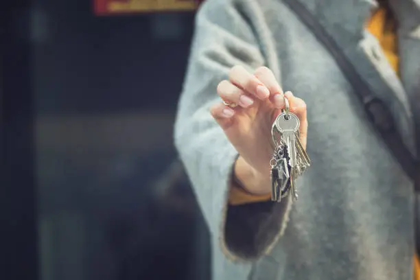 Close up of real estate agent showing keys of new apartment. Woman with new house keys.