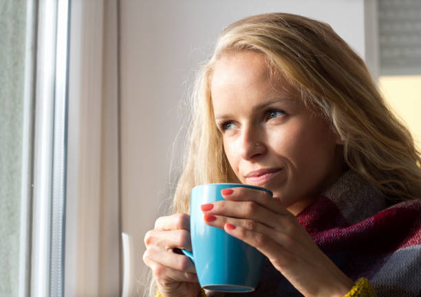 istock Woman drinking tea beside window 882361360