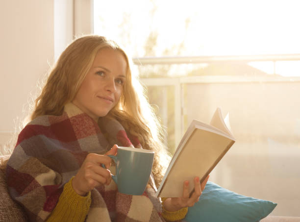 istock Woman drinking tea and reading book 882361552
