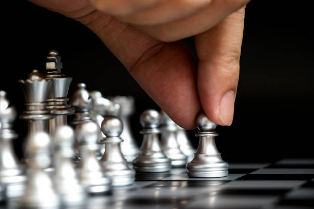 istock Business man hold pawn to first move in chess game (Concept for company strategy, vision or decision) 882362284