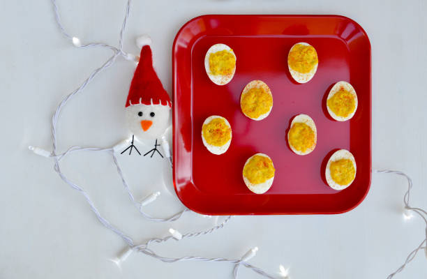 Winter Themed Deviled Eggs on a Red Plate with Holiday Lights and a Little Plush Chick with a Winter Hat