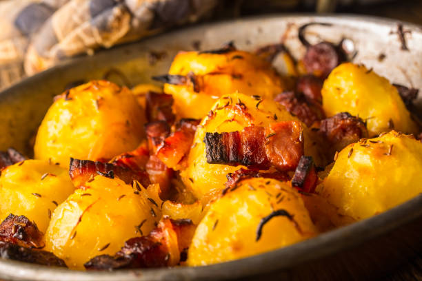istock Potatoes. Roasted potatoes with bacon onion and sausages on old oak table 882384708