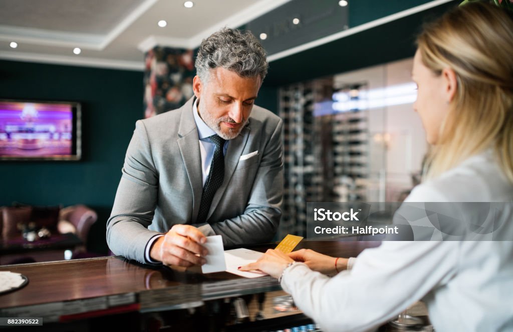 Mature businessman at hotel reception. Mature businessman checking in at hotel reception. Hotel Reception Stock Photo