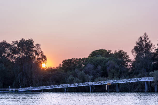 Sun fall Sunset in Seville on the trees of expo 92.  In the foreground the Guadalquivir River seville port stock pictures, royalty-free photos & images