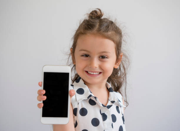 petite fille jouant avec son smartphone - elementary age focus on foreground indoors studio shot photos et images de collection