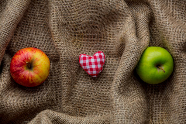 heart shape toy and apples on jute background. Autumn season
