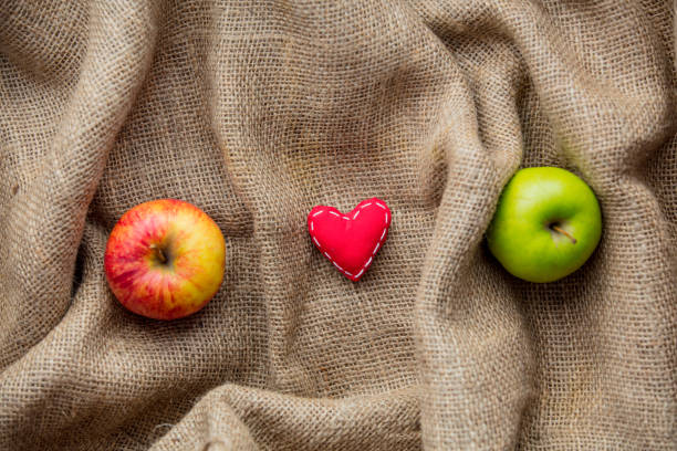 heart shape toy and apples on jute background. Autumn season