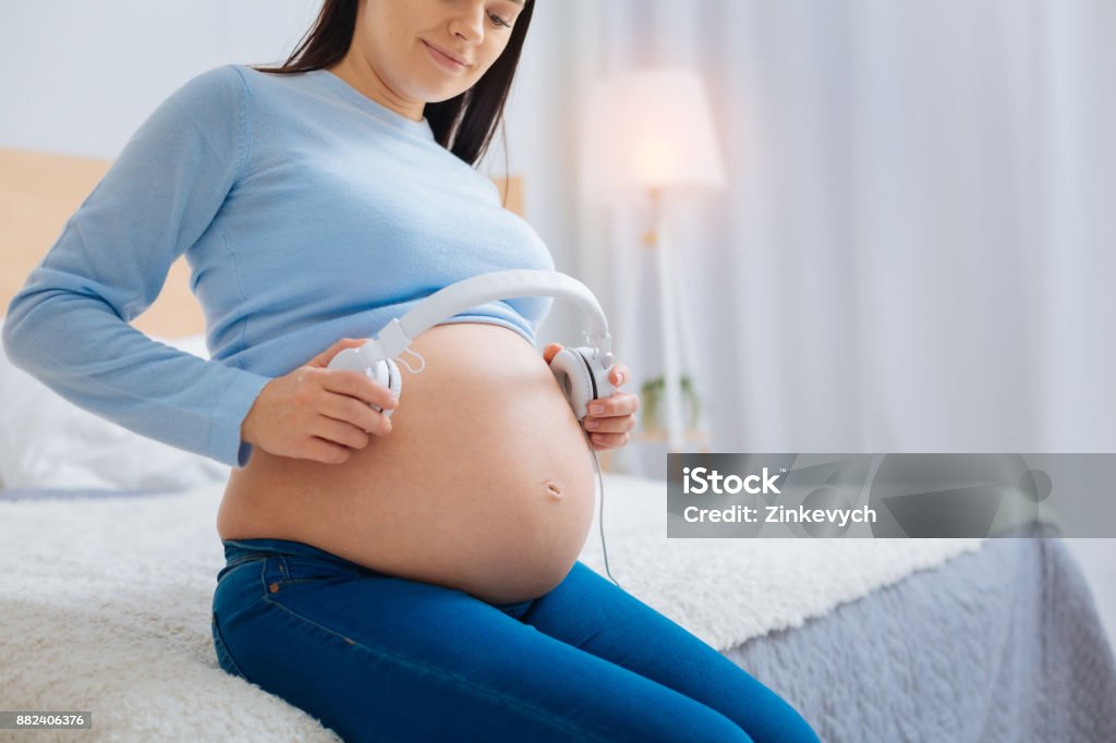 Relaxed Pregnant Woman Putting Headphones On Her Belly Stock Photo -  Download Image Now - iStock
