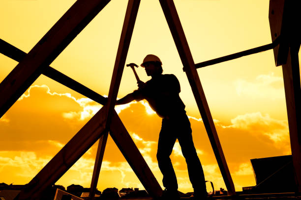 silhouette of roofer worker builder working on roof structure at construction site