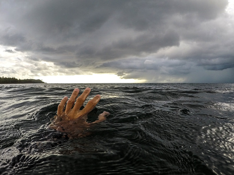 Hand reaching for horizon in the ocean