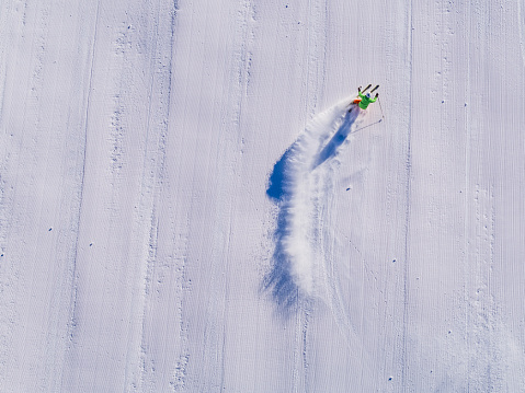 skier skiing on an empty ski-slope from drone perspective from straight above skis covered by snow no ski tracks visible on fresh prepared ski-piste