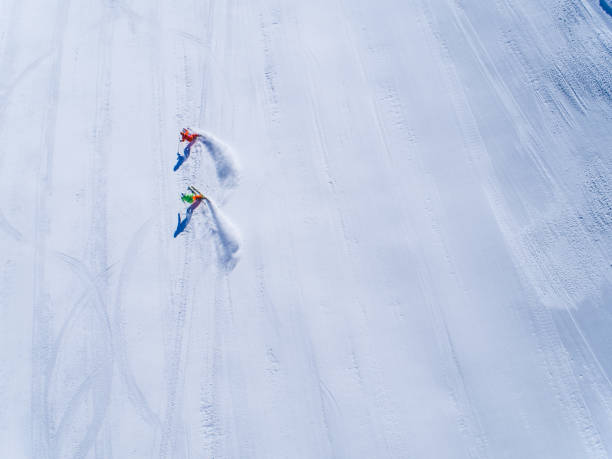 istock Winter Breaks - aerial view two skiers skiing 882436802