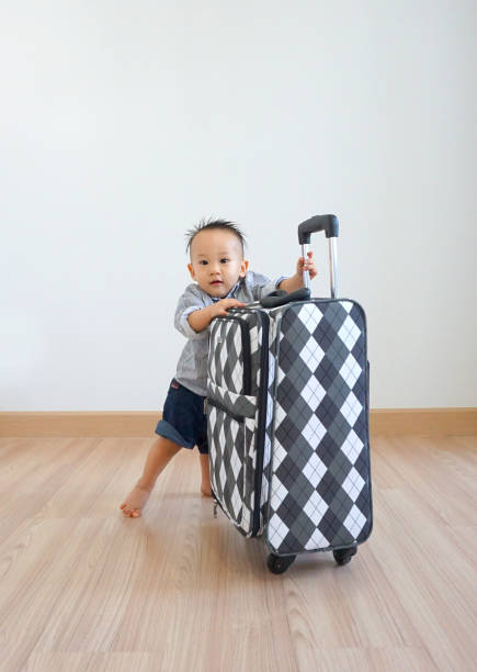 istock Little boy pushing a luggage in a room 882437338
