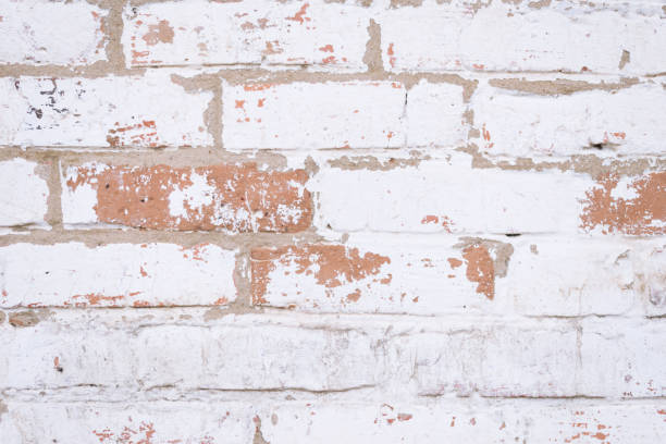 istock Old red brick wall with shabby damaged white plaster. 882448180