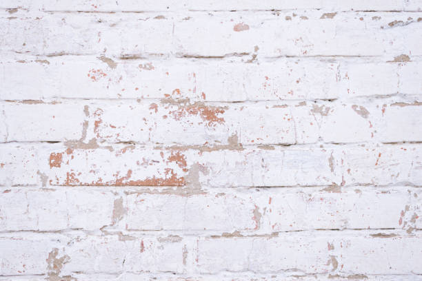 istock Old red brick wall with shabby damaged white plaster. 882448210