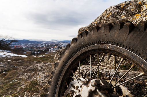 Wheel with spokes and brake disc plus Enduro motorcycle chain. Close-up shot at a background of a landscape