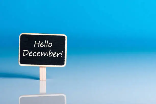 Photo of Hello december on sign at blue background with empty space for text, mockup. December 1st, the beginning of the Christmas and New Year holidays and sales