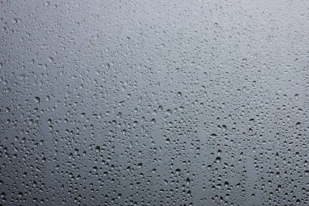 istock Rain drops on glass against the grey rainy sky 882494482