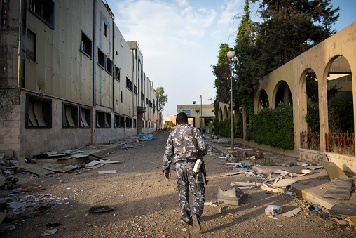 Mosul, Iraq - May 23, 2017: An Iraqi security guard walks in the ruins of Al-Salam hospital, one of the many institutions in Mosul that will take years to rebuild. The hospital was the scene of heavy fighting in late 2016, when the Iraqi government, with U.S. support, wrested control of this part of Mosul from ISIS.