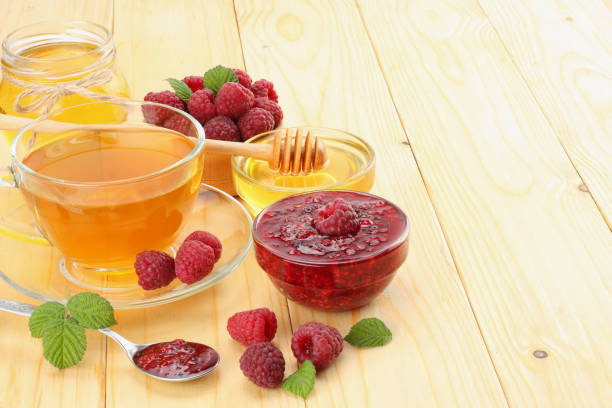 istock healthy background. raspberry with raspberry jam, honey and tea on light wooden background 882527654