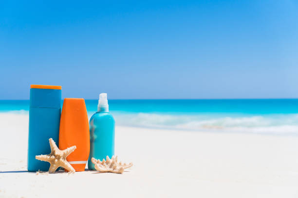 istock Suncream bottles, goggles, starfish on white sand beach background ocean 882527694