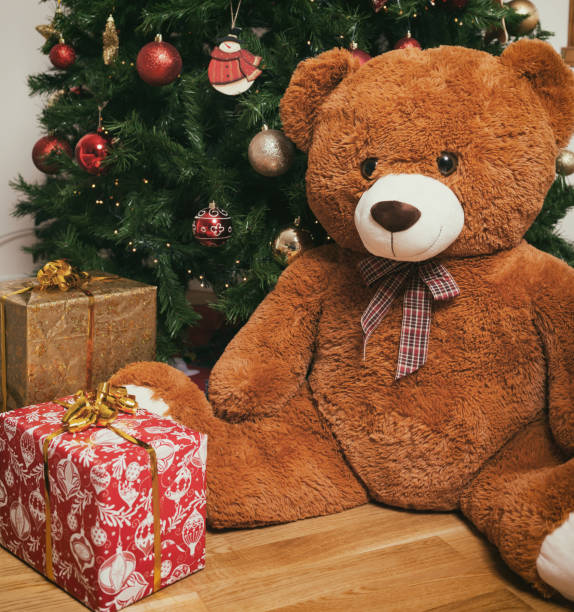 istock Teddy bear near christmas tree with gifts 882535008