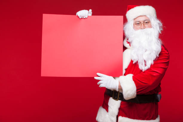 istock Santa Claus pointing in blank advertisement banner isolated on red background with copy space red leaf 882535128