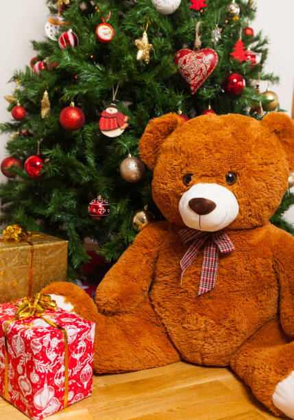 istock Teddy bear near christmas tree with gifts 882535510