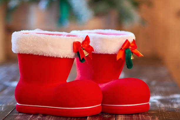 istock Red Christmas boot with white border and small bells on wooden table 882558028