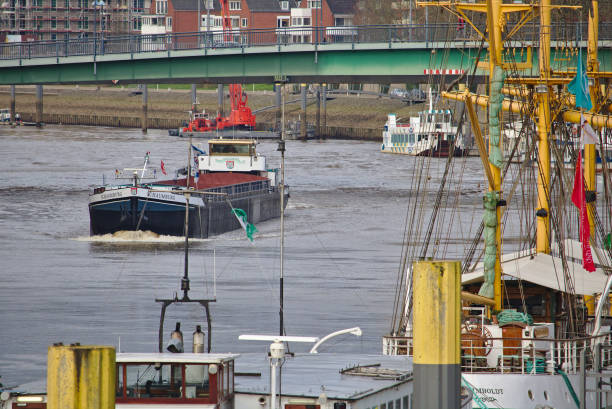 Inland vessel passing under a bridge across the river Weser with moored ships in the foreground stock photo