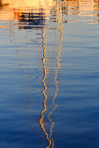 Reflections of a sailboat in the water.