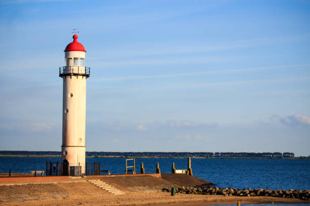 istock Red and white lighthouse in front of blue sky during the sunset 882584670