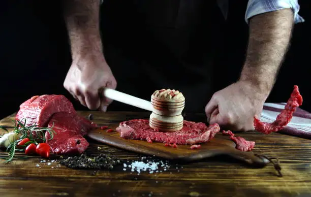 a man beats beef on a cutting board
