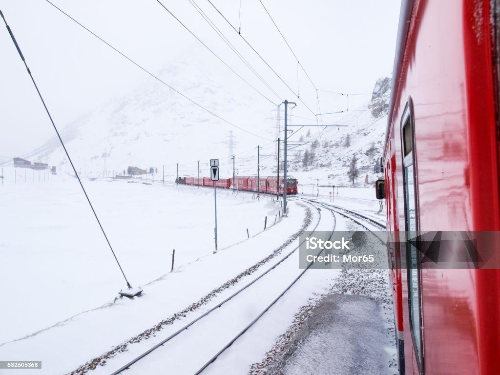 trains of the Rhaetian Railway Bernina, Switzerland - April 27, 2016: trains of the Rhaetian Railway in transit meet along the Tirano - St.Moritz line during a snowy day. Autumn Stock Photo