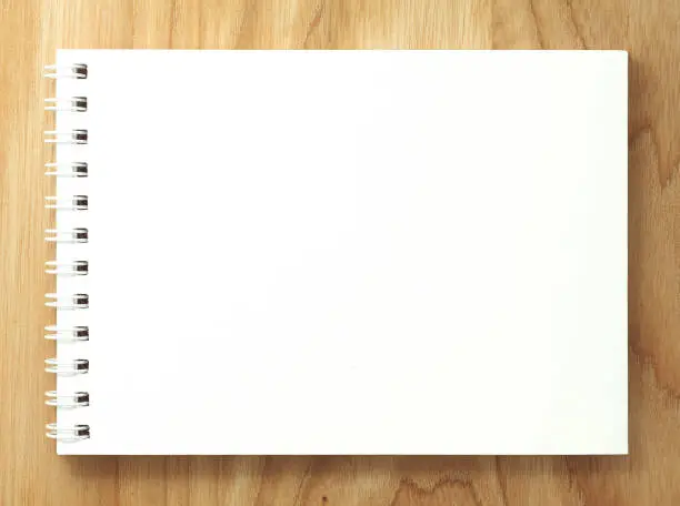 Top view of spiral blank notebook on wood desk background