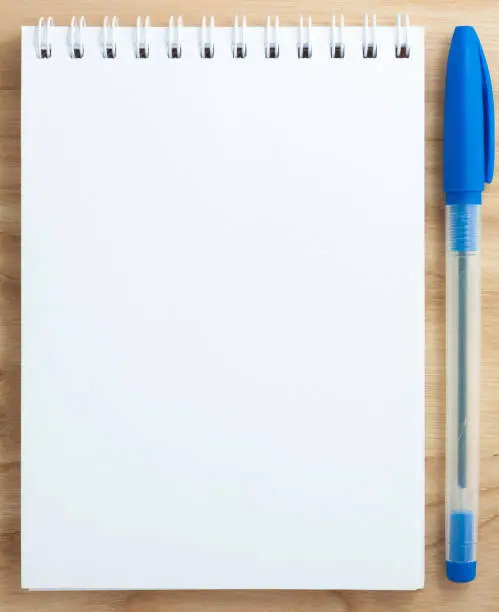 Top view of open spiral blank notebook with pencil on wood desk background