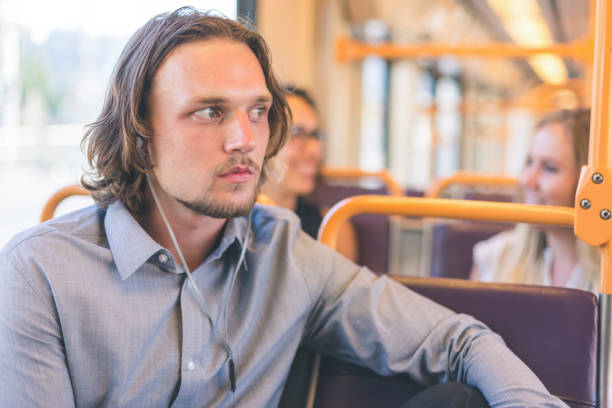 man wearing headphones riding public transportation - bus riding public transportation businessman imagens e fotografias de stock