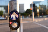 City traffic concept: Pedestrian press to go button at intersection on blurred urban background.