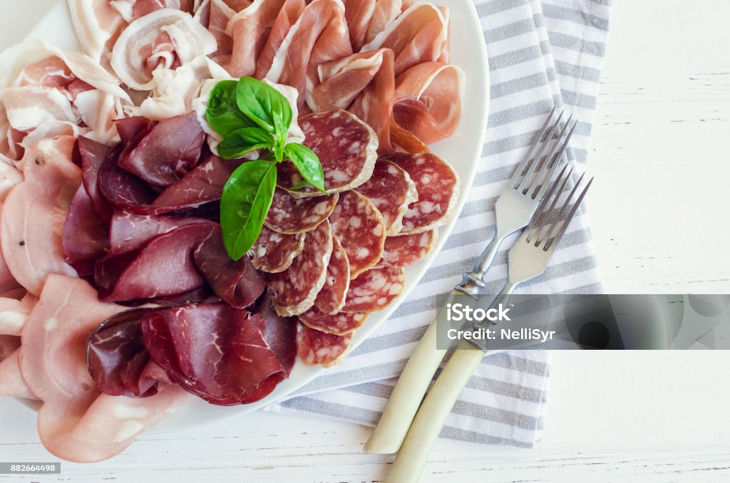 Cold smoked meat plate Cold smoked meat plate with pork, prosciutto, salami and bresaola on white wooden background. Wine appetizer set. Italian food. Top view. Above Stock Photo