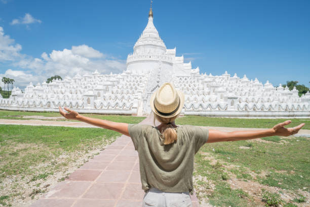 Young adult expressing positivity arms outstretched, traveling in Southeast Asia and visiting white temple, Myanmar. People travel concept.