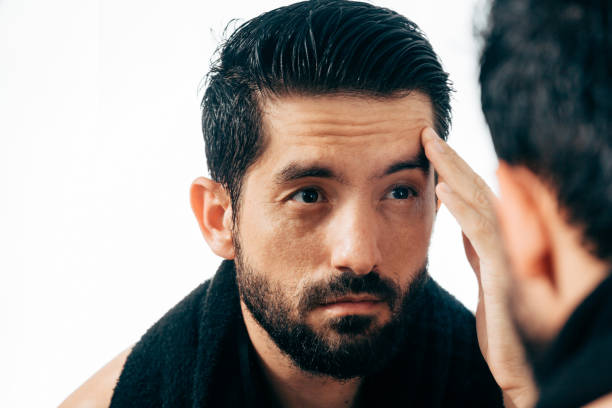 istock Man in front of mirrror looking at his wrinkles 882701022