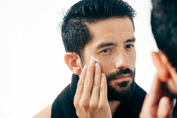 istock Handsome man applying facial cream in bathroom while looking at mirror 882701136