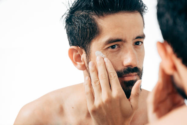 istock Handsome man applying facial cream in bathroom while looking at mirror 882701364