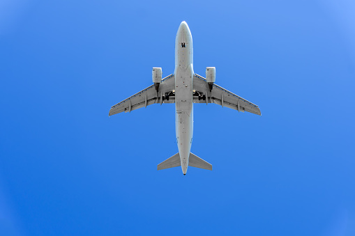 large modern plane flies in a blue sky, close-up, bottom view