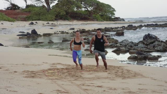 4K Slow Mo: Hawaiian Couple Exercising On Beach with Rope Ladder