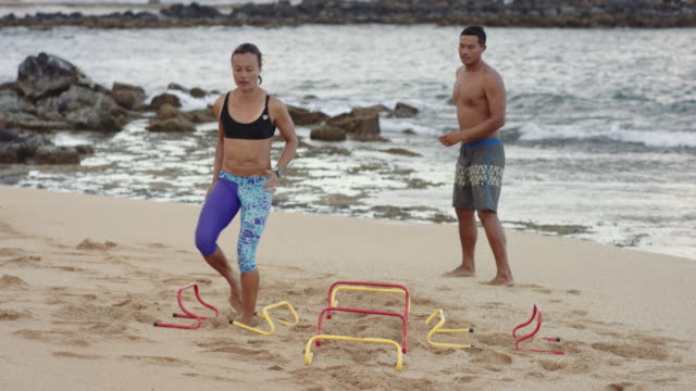 4K Slow Mo: Woman Doing Agility Exercise on the Beach with Her Male Partner
