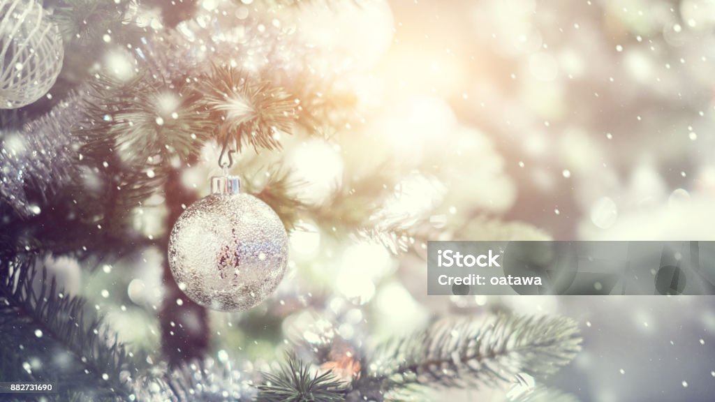 White and silver bauble hanging from a decorated Christmas tree with background. Closeup white and silver and bauble hanging from a decorated Christmas tree with bokeh, copy space, Xmas holiday background. Christmas Tree Stock Photo